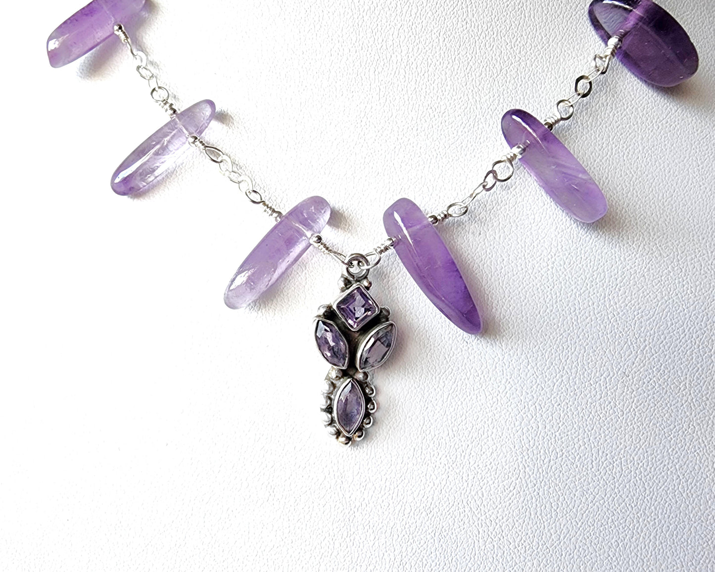 Amethyst Sterling Silver almost fan style Necklace with Decorative Silver pendant with sparkly faceted stones and wire wrapped long stones and silver chain on white background 