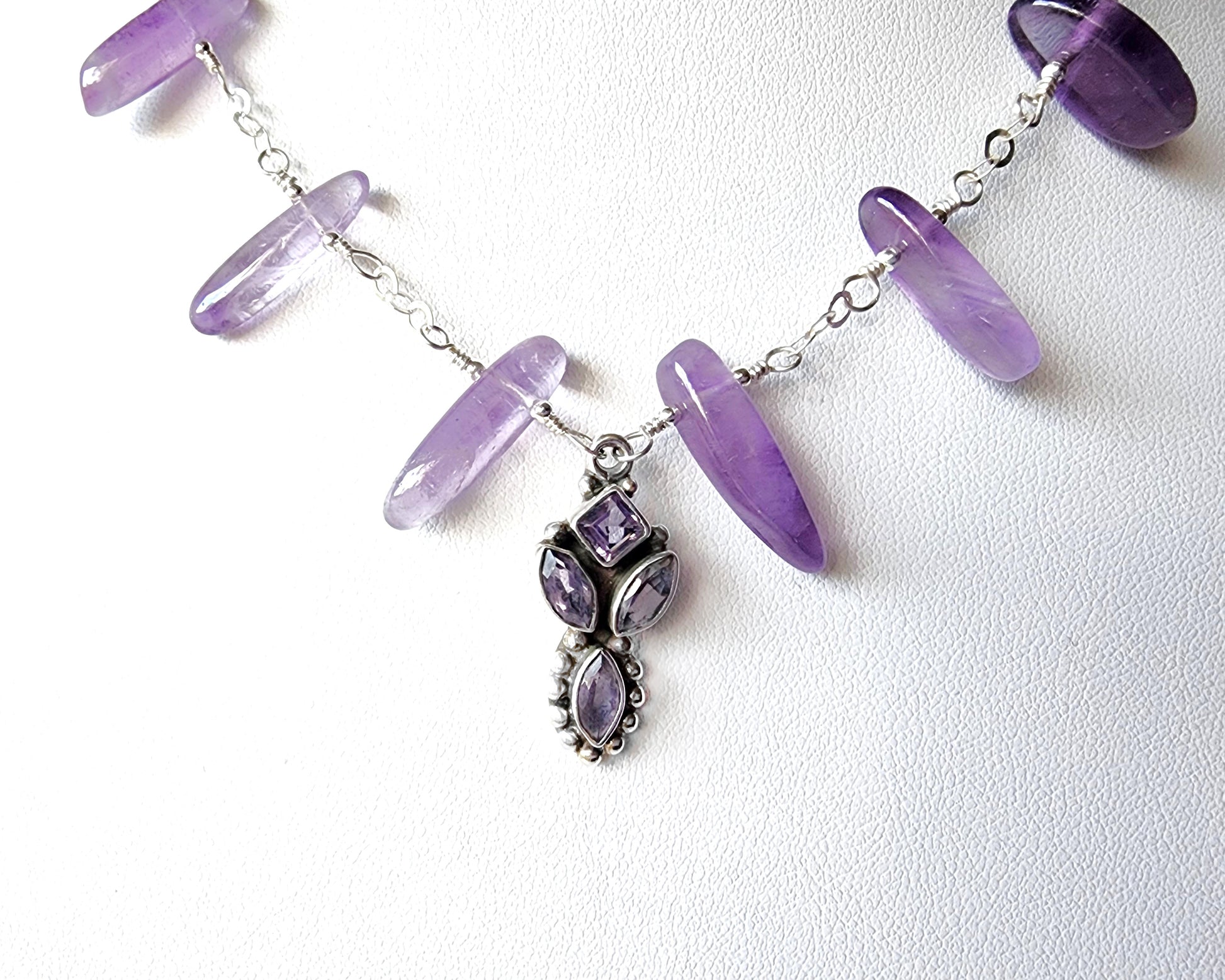 Amethyst Sterling Silver almost fan style Necklace with Decorative Silver pendant with sparkly faceted stones and wire wrapped long stones and silver chain on white background 