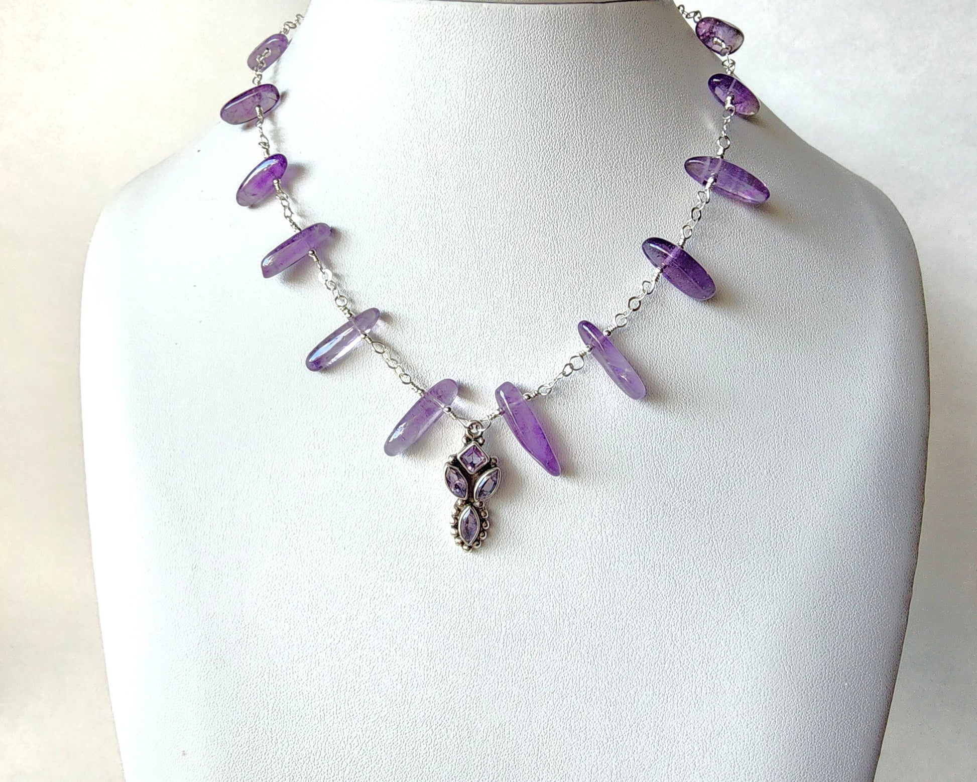 Amethyst Sterling Silver almost fan style Necklace with Decorative Silver pendant with sparkly faceted stones and wire wrapped long stones and silver chain on white display bust