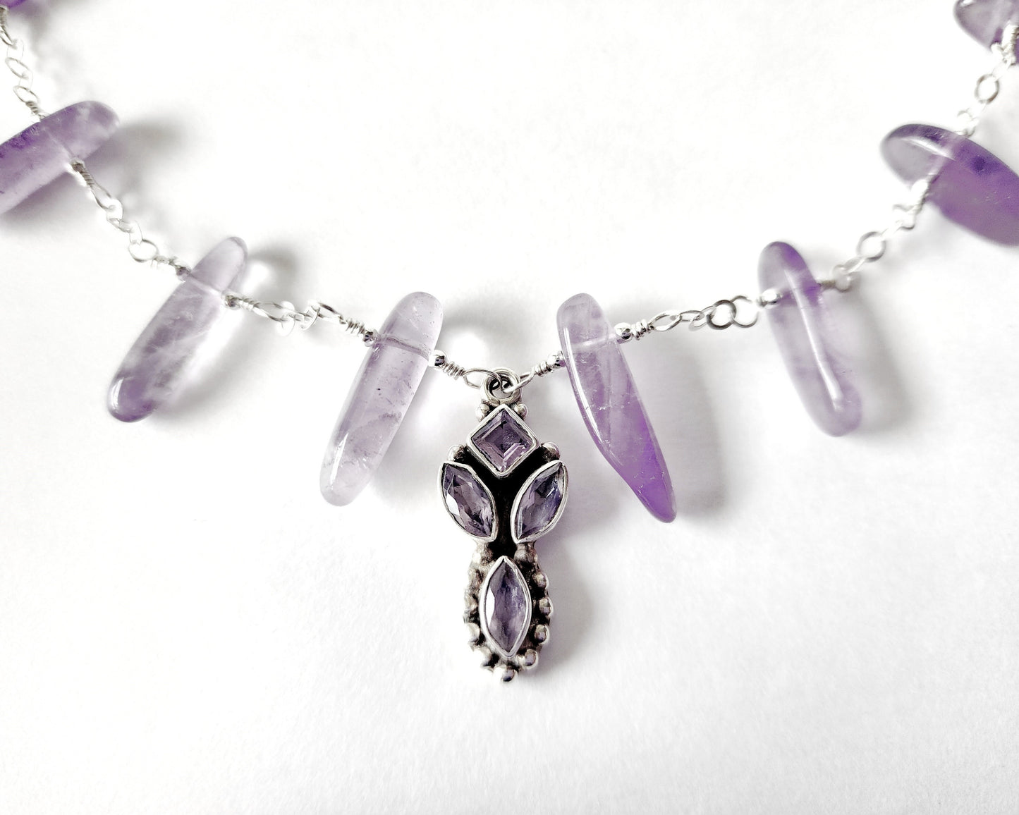 Amethyst Sterling Silver almost fan style Necklace with Decorative Silver pendant with sparkly faceted stones and wire wrapped long stones  on white background 