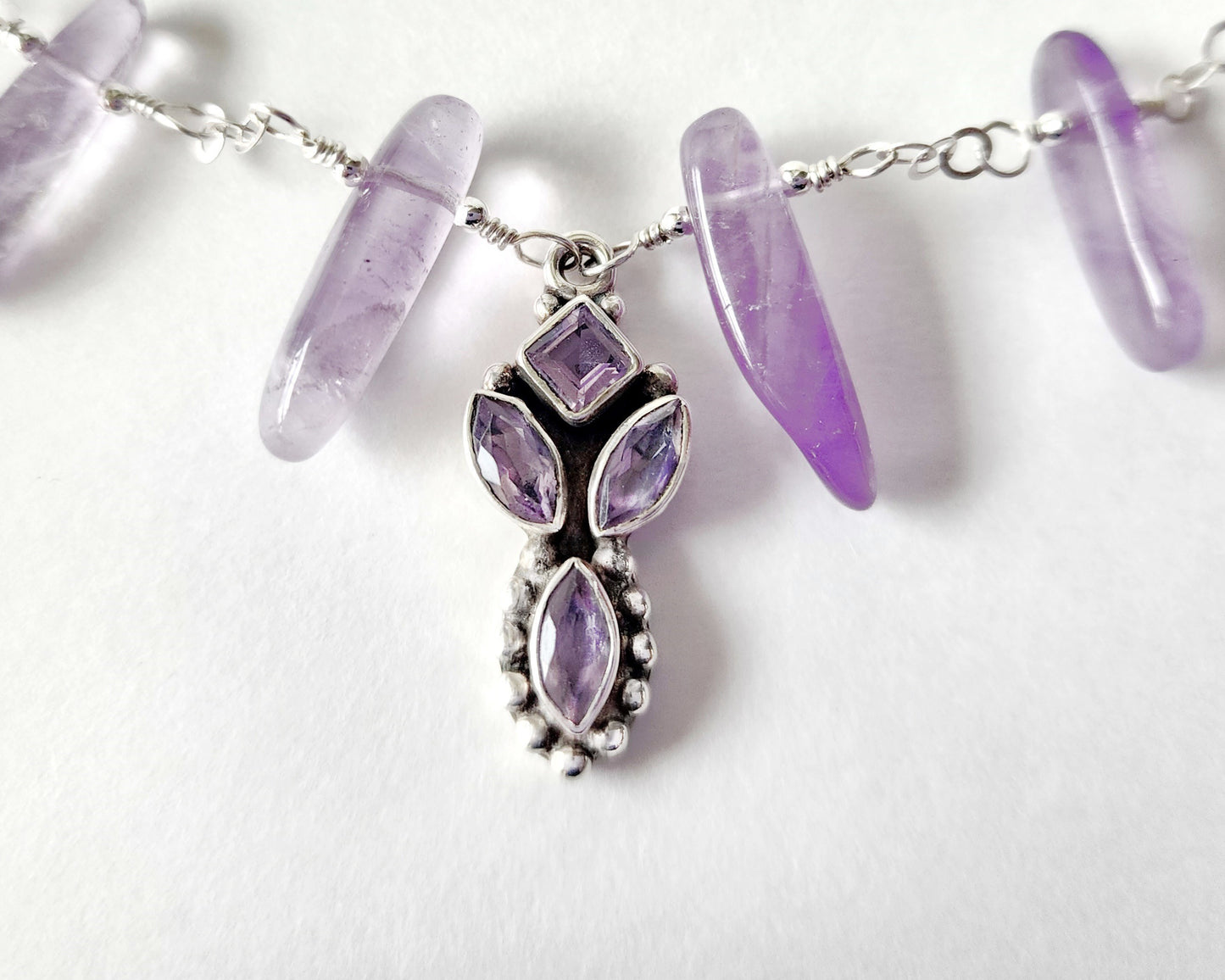 Amethyst Sterling Silver almost fan style Necklace with Decorative Silver pendant with sparkly faceted stones and wire wrapped long stones on white background 
