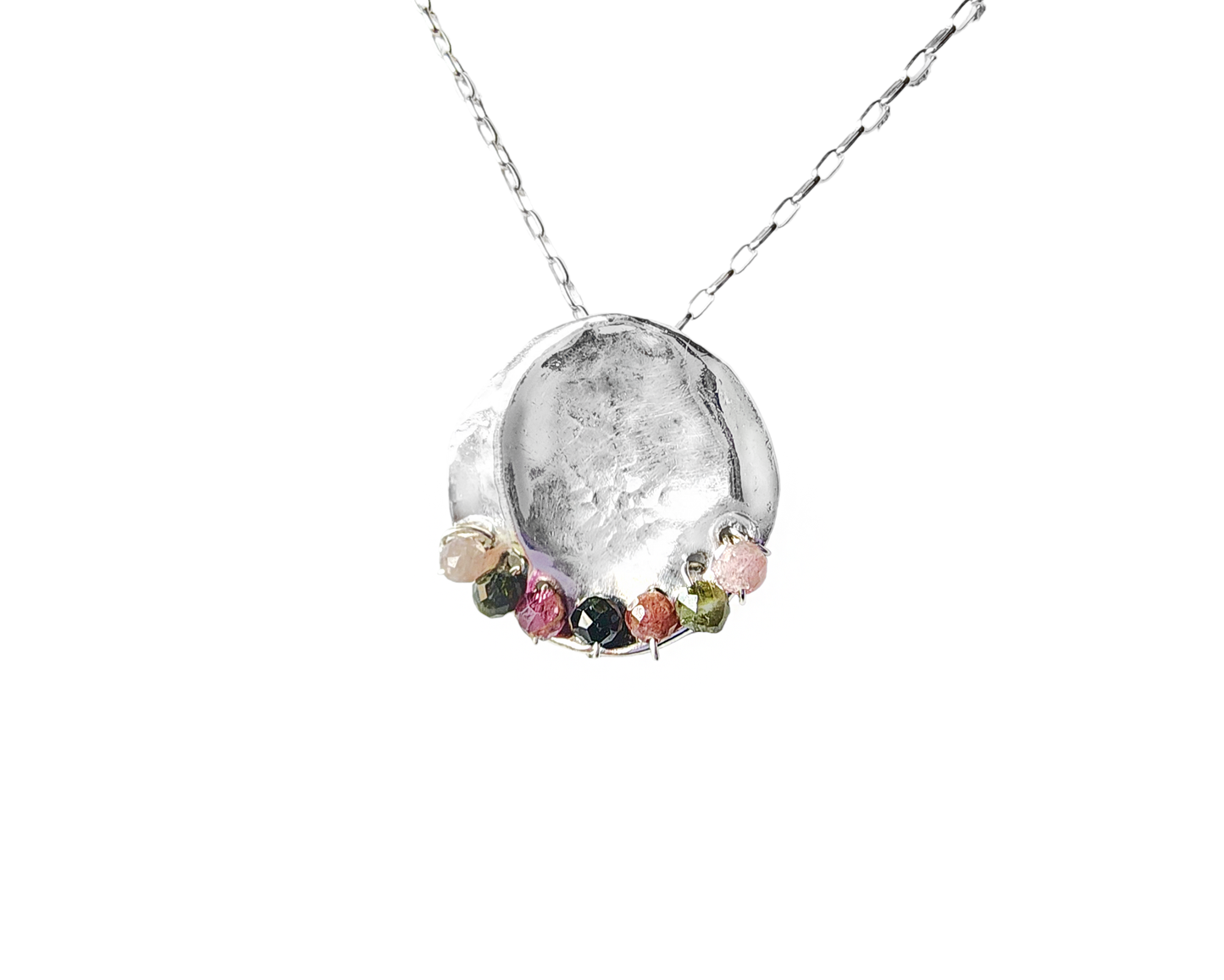 Tourmaline Transformation Pendant, a round Sterling Silver Textured Circle with multi color Tourmaline stones on the base: Pink, green and black. Pendant on fine Rolo chain.