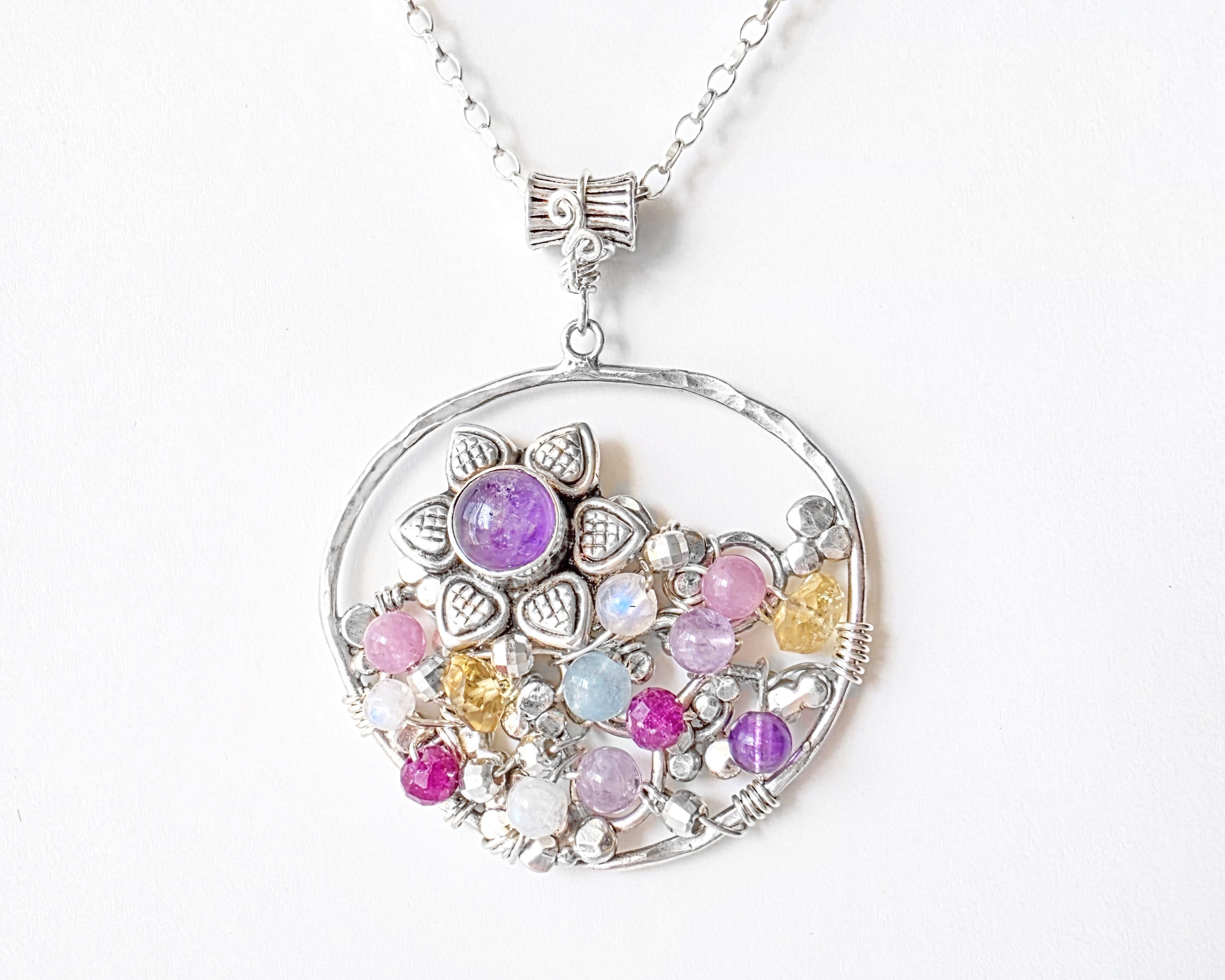 Round Silver pendant with sparkly open work design and colorful Gemstones, Amethyst, Ruby, Citrine, Amethyst, Rose Quartz, Moonstone, Aquamarine on chain, on white background