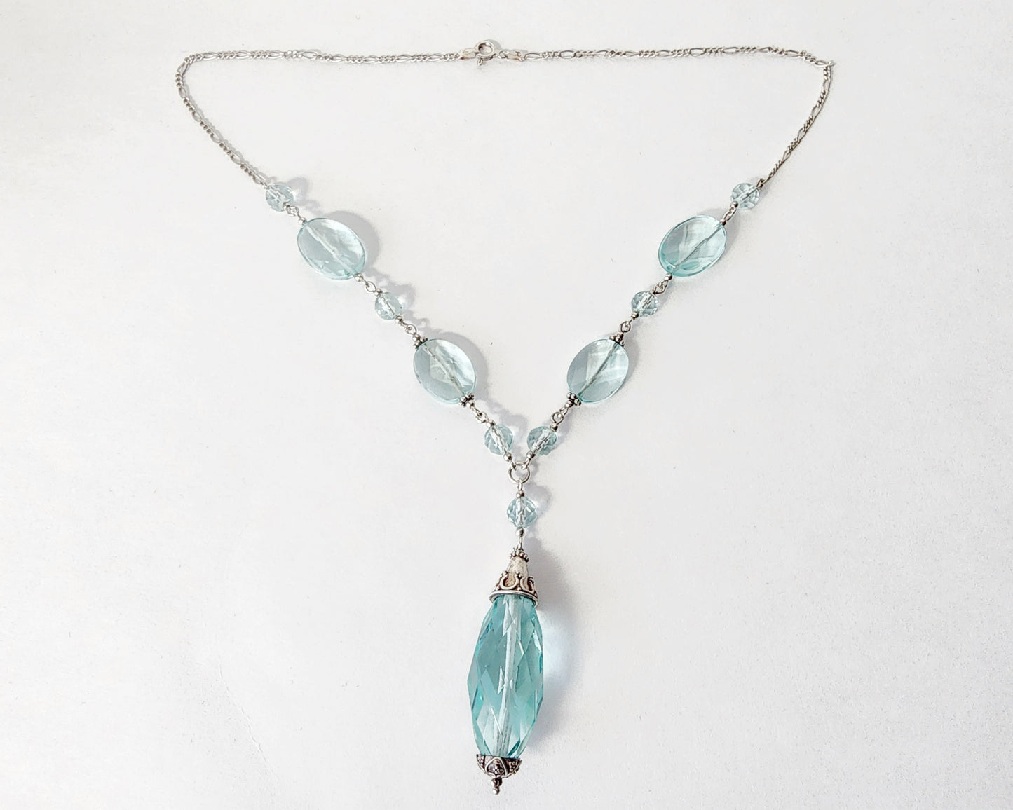 Art Deco style Aquamarine necklace made with large faceted, sparkly pale aqua blue translucent synthetic Aquamarine stones and Sterling Silver beads and chain on white background