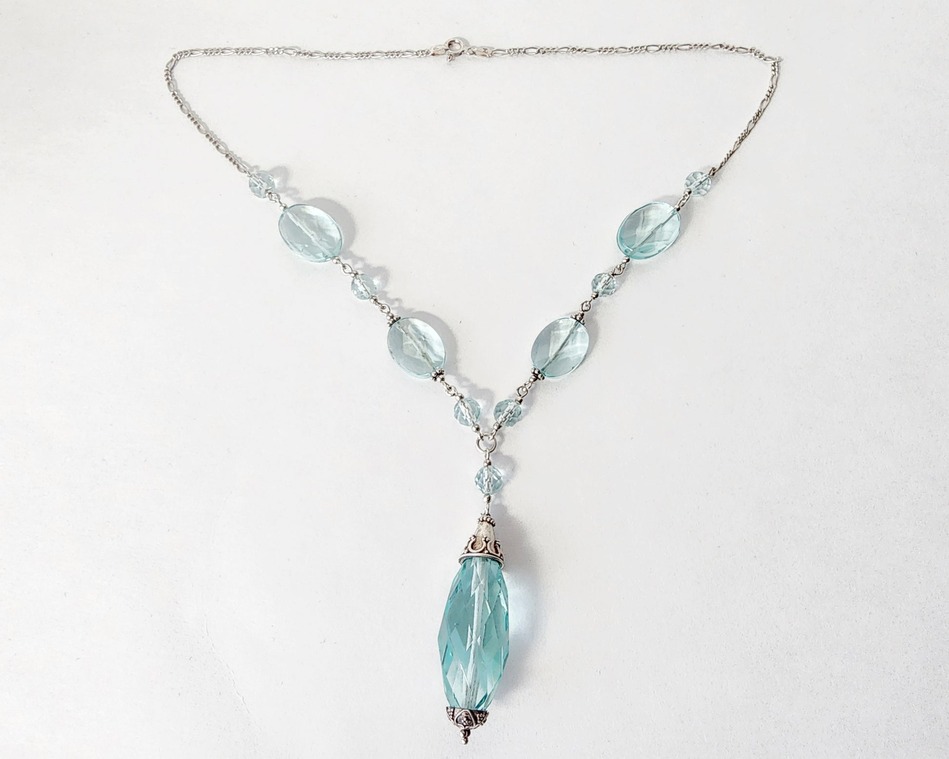 Art Deco style Aquamarine necklace made with large faceted, sparkly pale aqua blue translucent synthetic Aquamarine stones and Sterling Silver beads and chain on white background