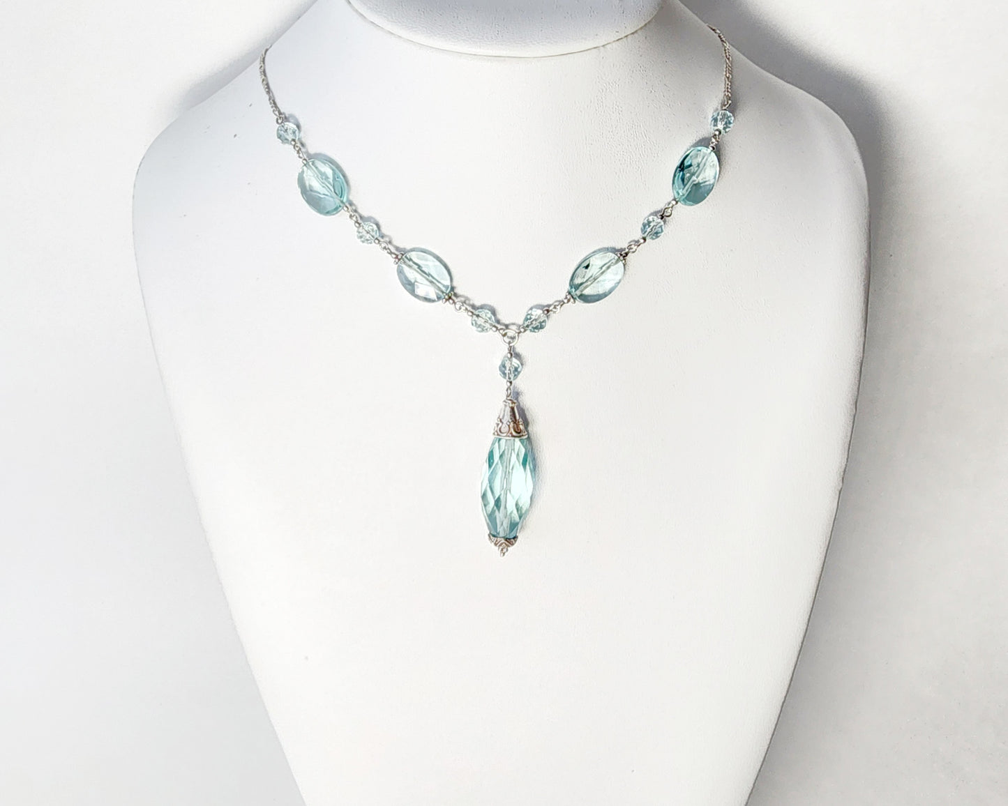 Art Deco style Aquamarine necklace made with large faceted, sparkly pale aqua blue translucent synthetic Aquamarine stones and Sterling Silver beads and chain on white background