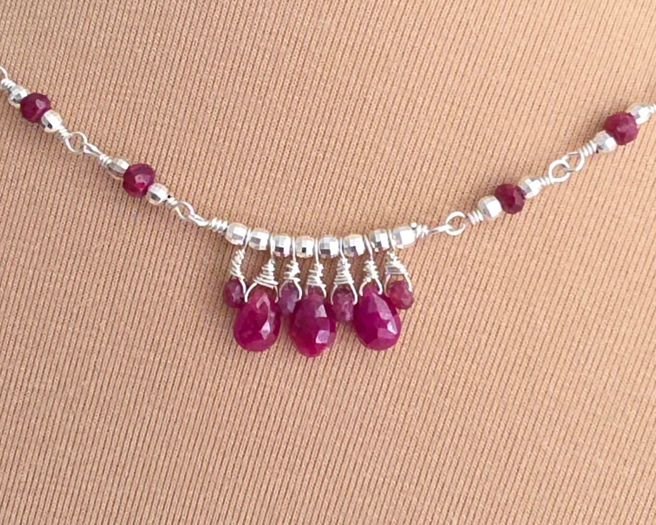 Silver and red Ruby necklace on beige background 