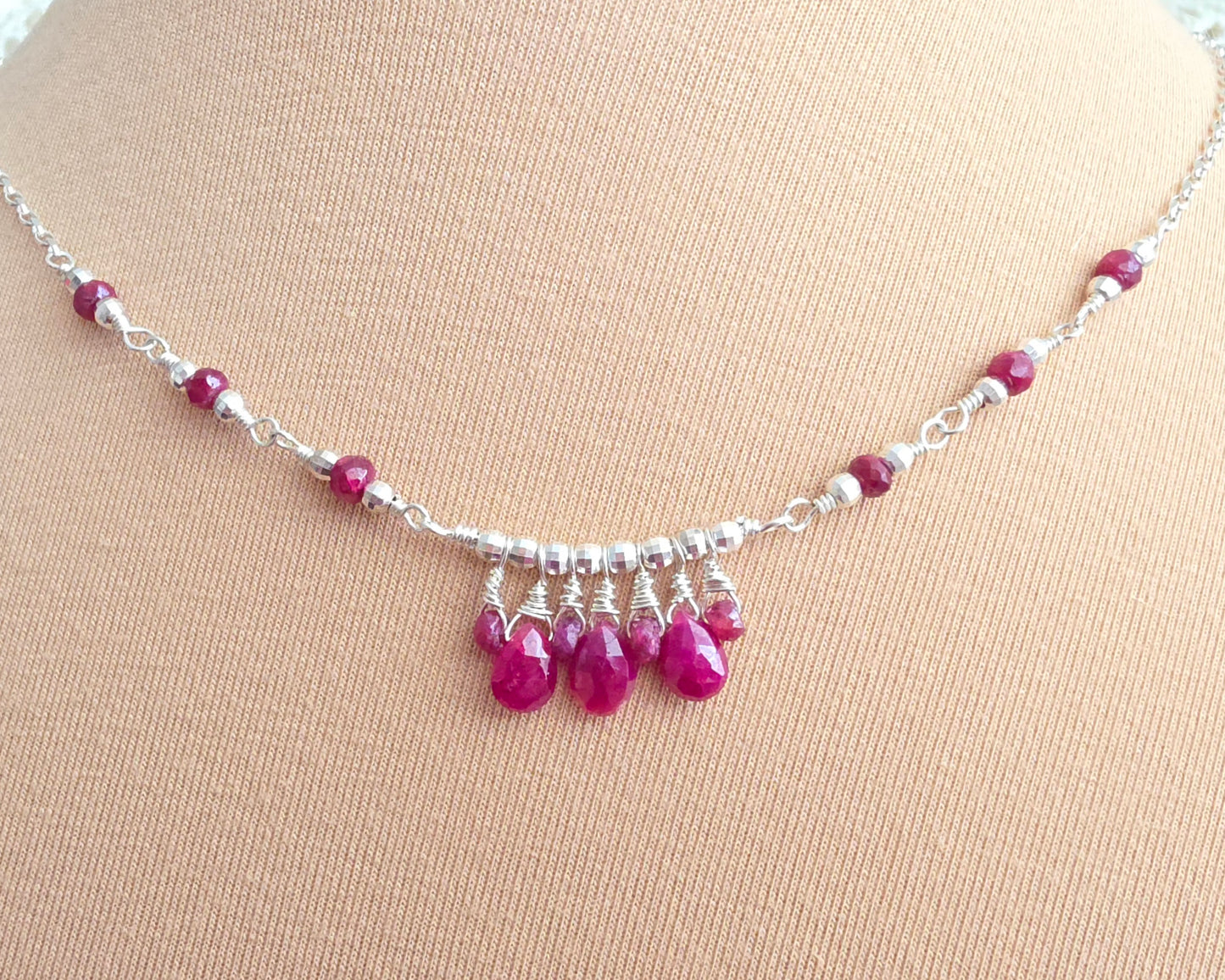 Silver and red Ruby necklace on beige background 