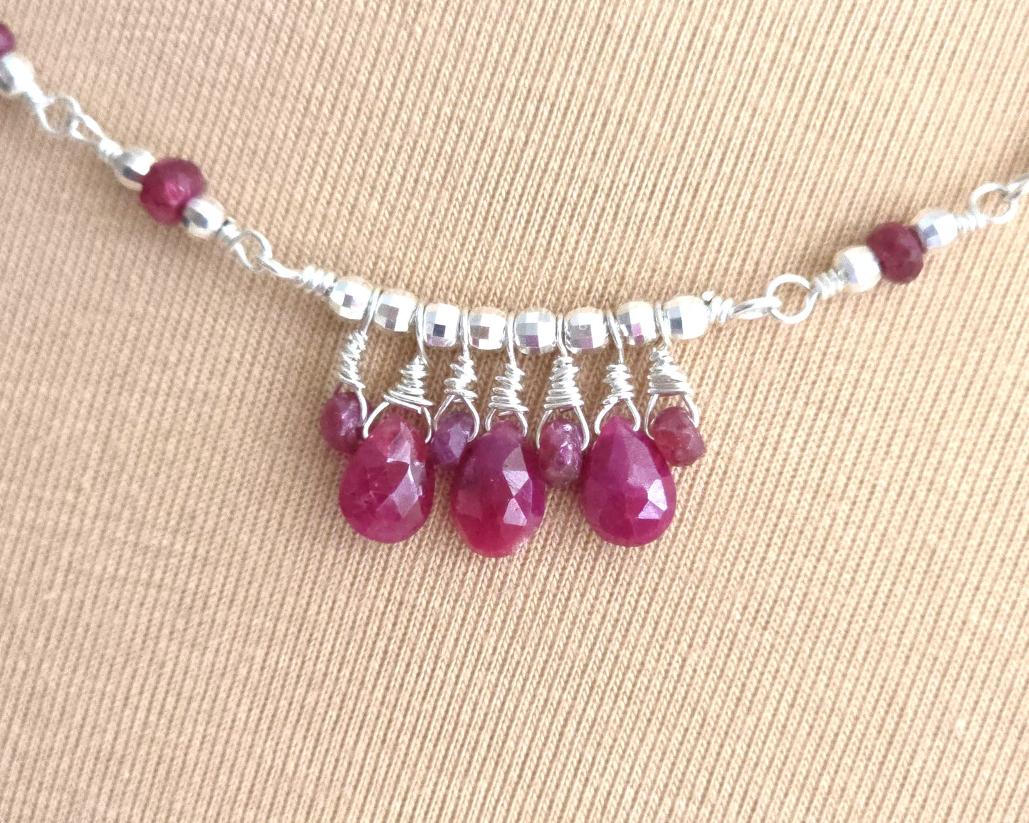 Silver and red Ruby necklace on beige background 