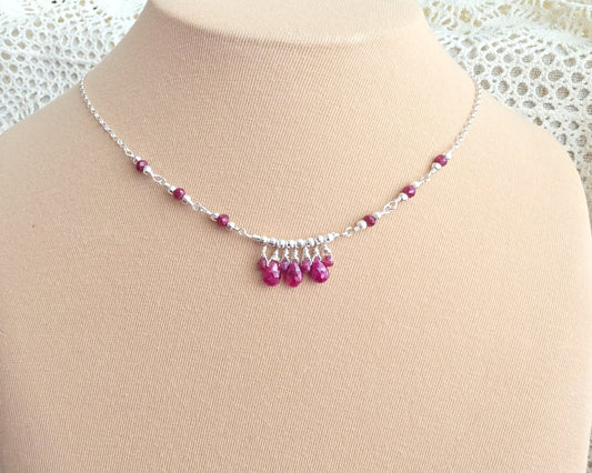 Silver and red Ruby necklace on beige display bust and lace background 