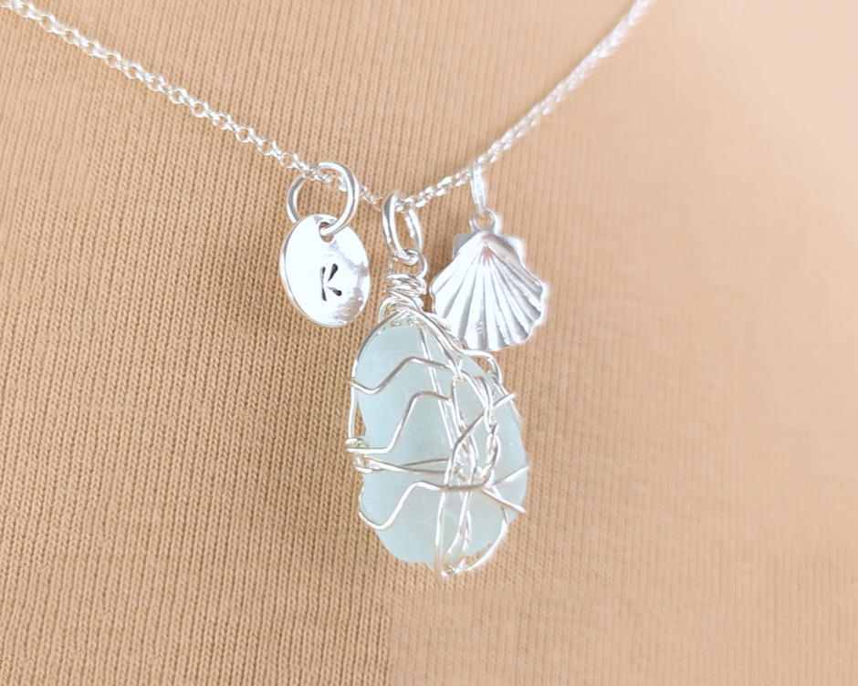 Silver Sea Glass Necklace with Aqua blue Sea Glass wire wrapped with shell & initial pendants on chain with beige background