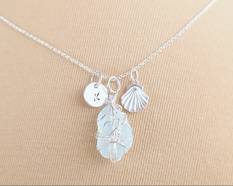 Silver Sea Glass Necklace with Aqua blue Sea Glass wire wrapped with shell & initial pendants on chain with beige background