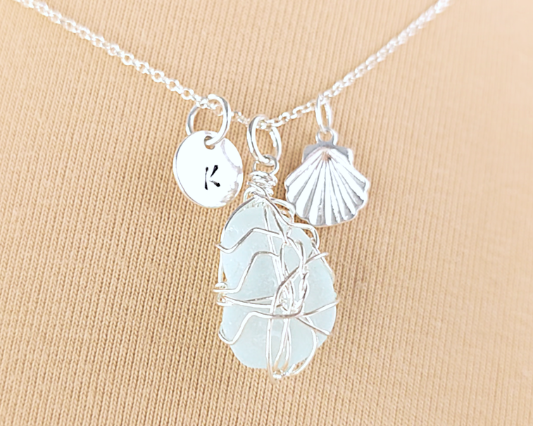 Silver Sea Glass Necklace with Aqua blue Sea Glass wire wrapped with shell & initial pendants on chain with beige background