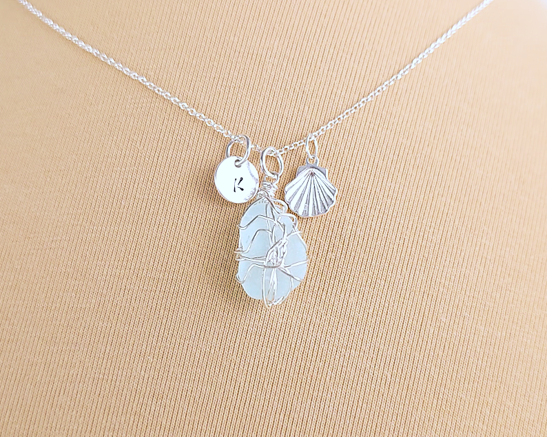 Silver Sea Glass Necklace with Aqua blue Sea Glass wire wrapped with shell & initial pendants on chain with beige background 