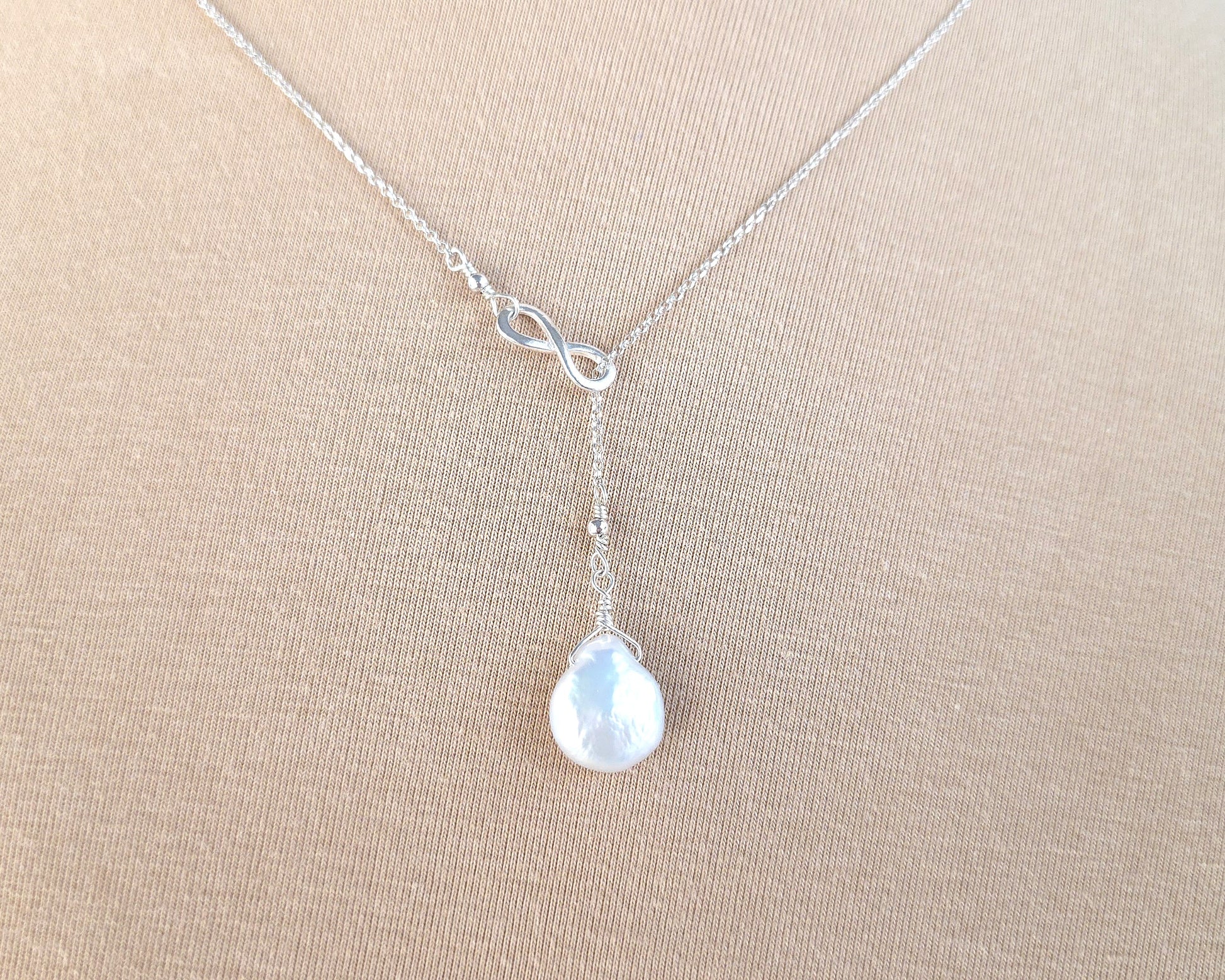 Large Pearl Drop Sterling Silver Infinity Lariat Necklace on beige display bust 