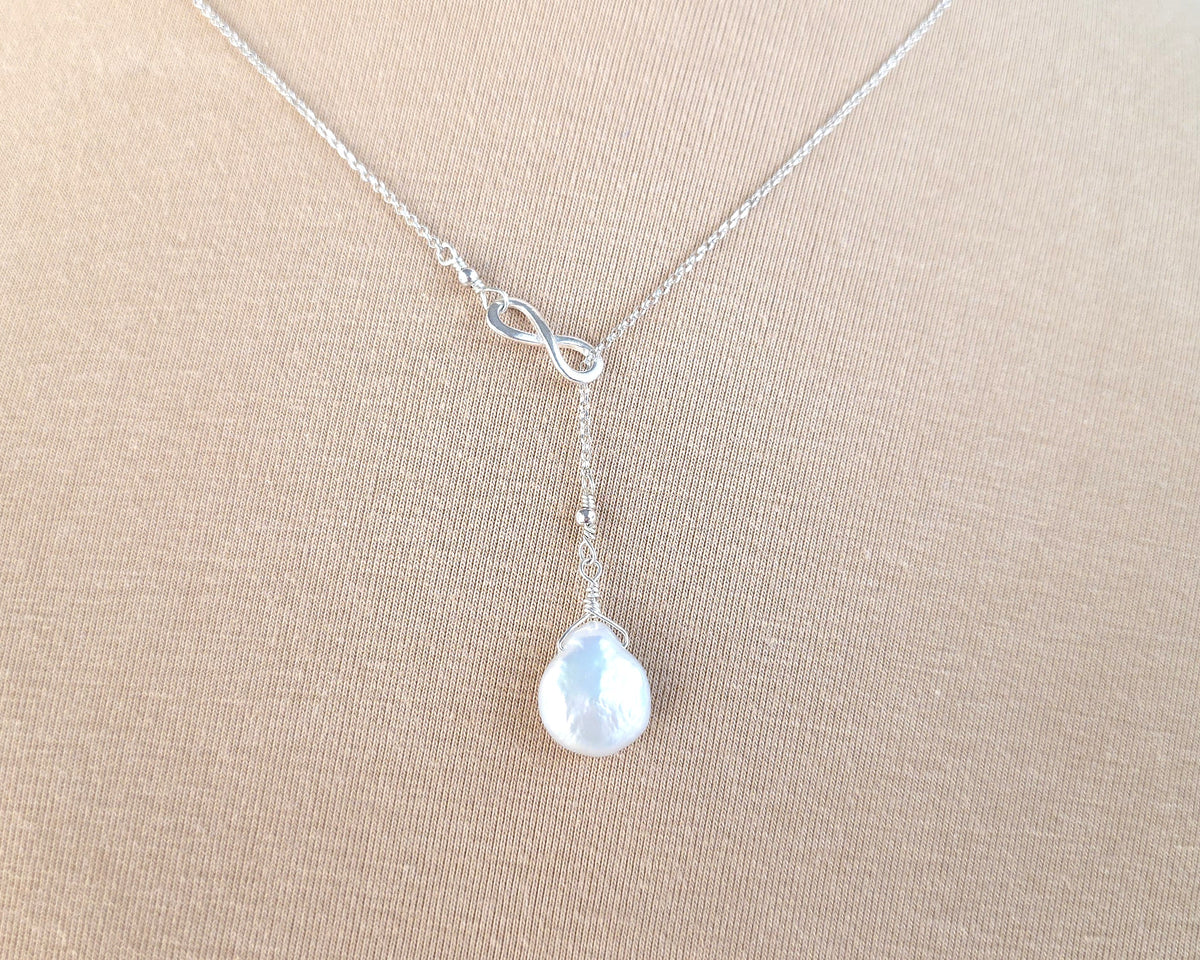 Large Pearl Drop Sterling Silver Infinity Lariat Necklace on beige  background