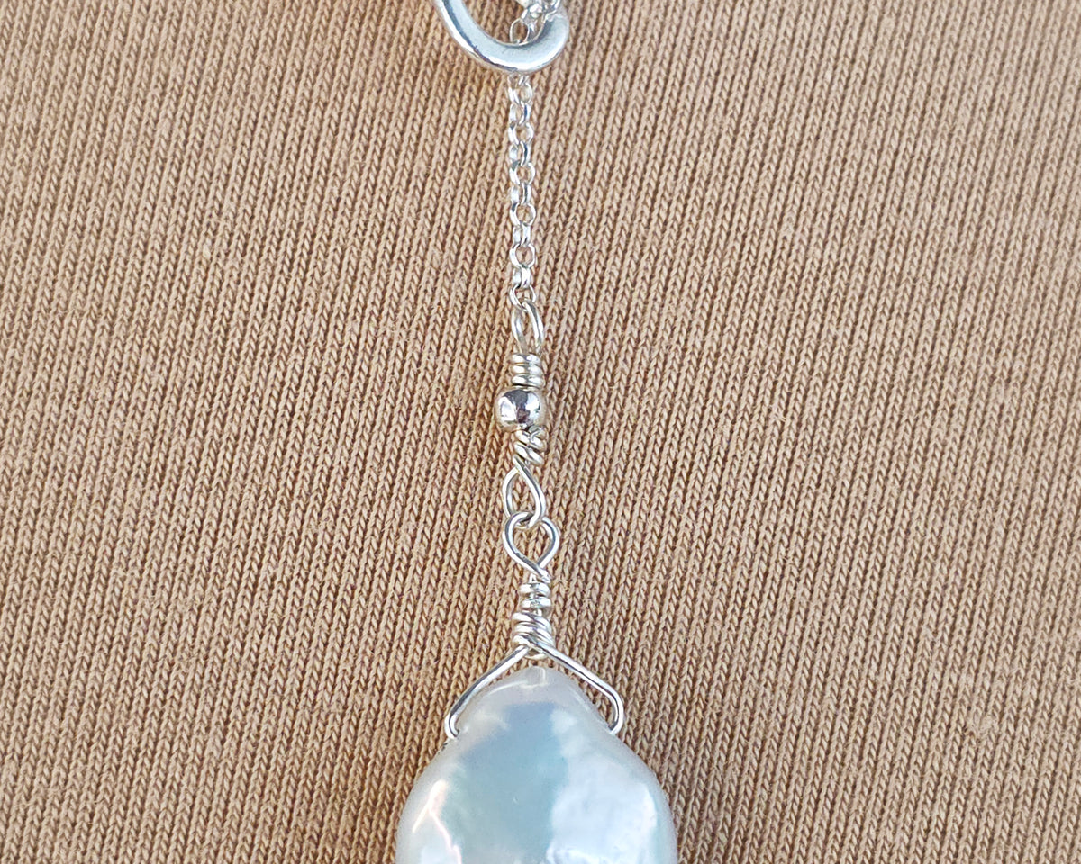 Large Pearl Drop Sterling Silver Infinity Lariat Necklace on beige  background