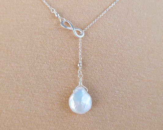 Large Pearl Drop Sterling Silver Infinity Lariat Necklace on beige display 