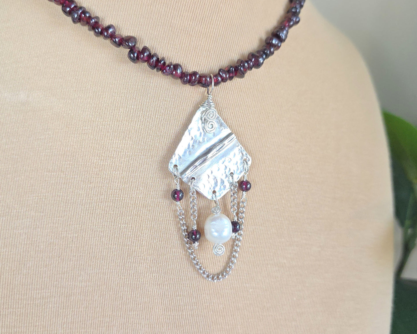 Deep Red stone beaded lariat style necklace with a Large Silver pendant with dangling stones white pearl and chains on beige display bust 