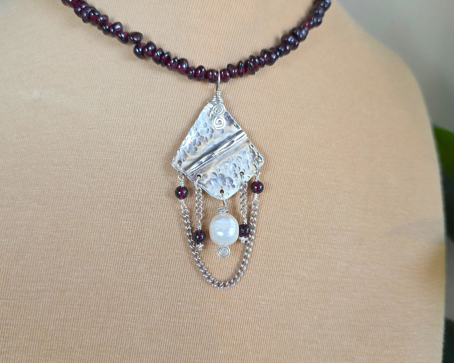 Deep Red stone beaded lariat style necklace with a Large Silver pendant with dangling stones white pearl and chains on beige display bust 