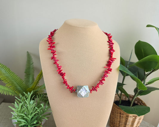 Handmade beaded red branch coral necklace with large Abalone bead in front on beige display bust 