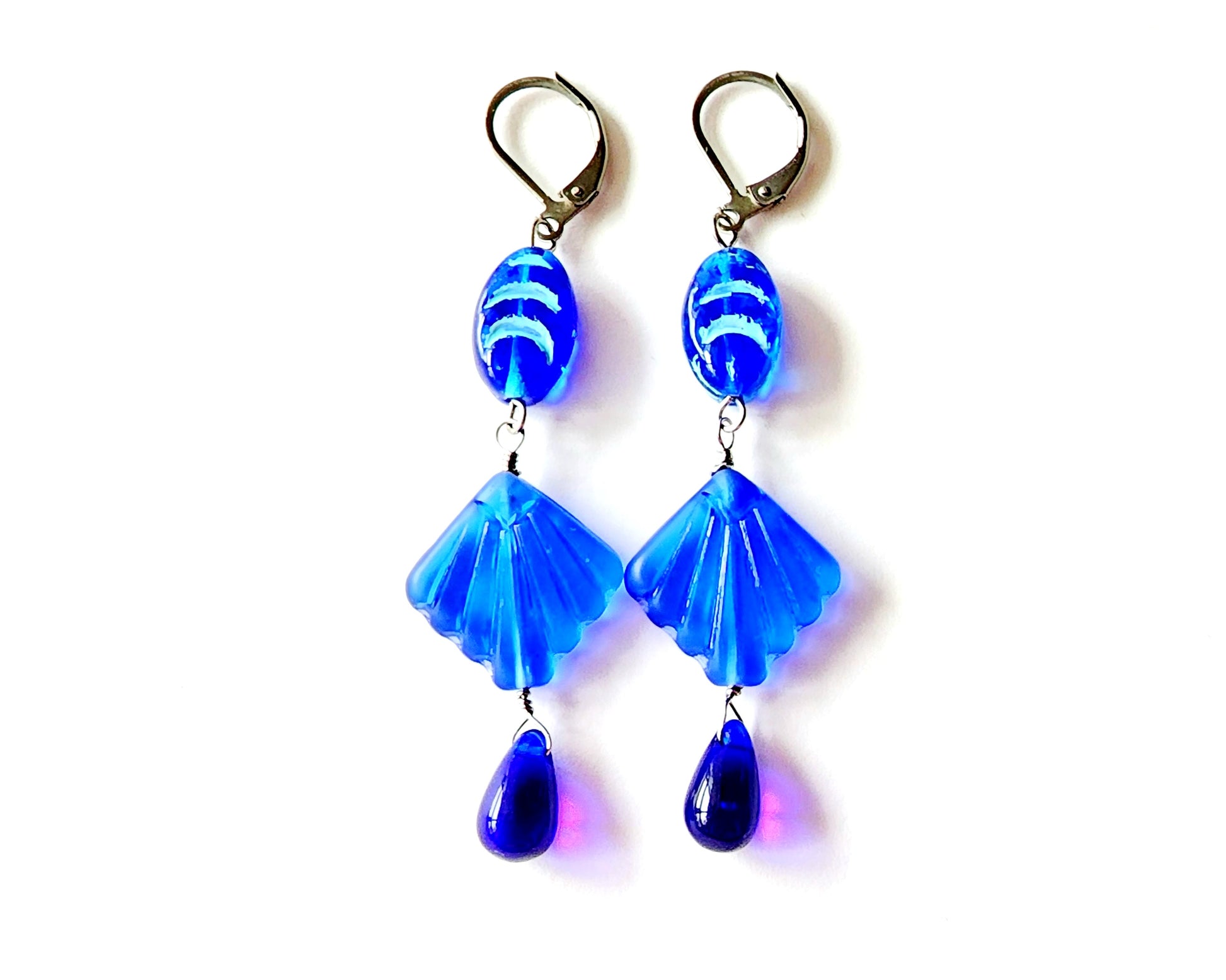 Extra Long Blue Shell Ocean Theme Earrings with sapphire blue color glass shell, wave design bead and drop shape beads on the ends. The metals is a silver color Stainless Steel.