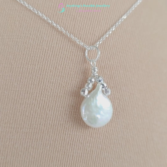 Video of  a Handmade Sterling Silver Pearl Pendant with a large rounder drop shape white freshwater Cultured Pearl with sparkly silver beads wire wrapped to a round bail on silver chain with beige background 