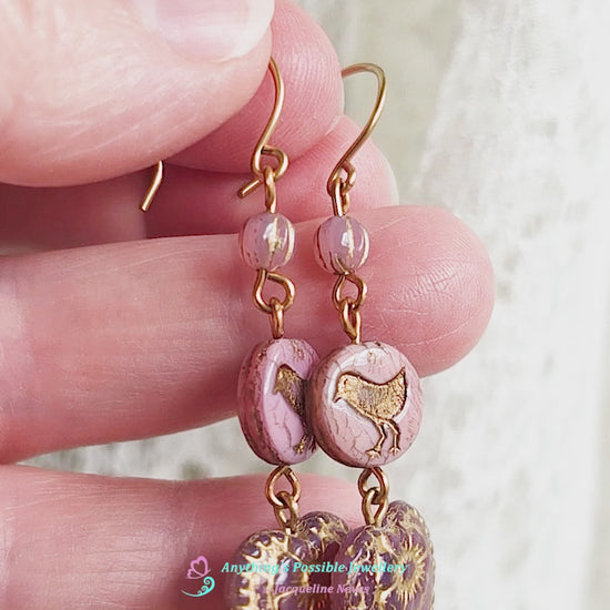 Video of long pink and gold earrings with large hearts and sparrow birds