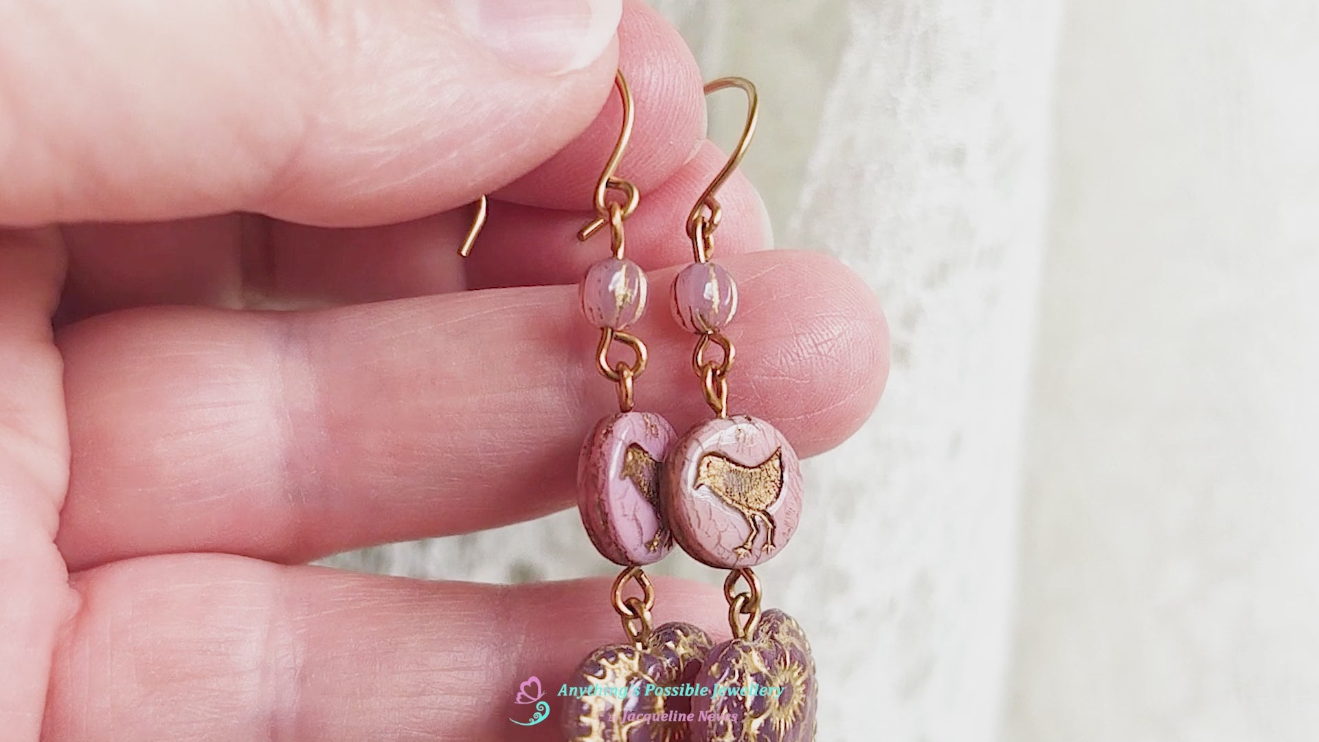 Video of long pink and gold earrings with large hearts and sparrow birds