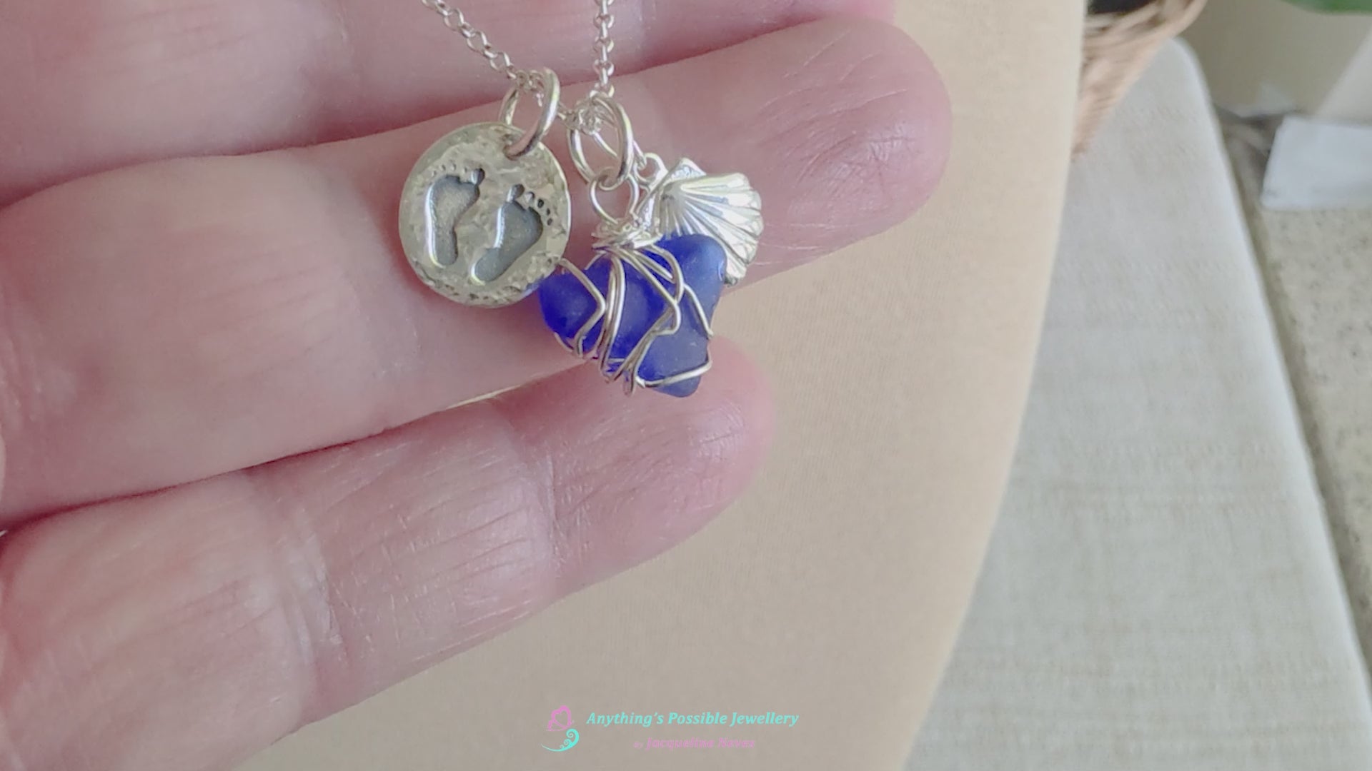 Video of Sterling Silver three charm necklace with a deep blue sea glass wire wrapped pendant with shell and footprints pendants on chain