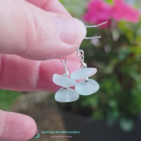 Video of Pale Aqua blue Sea glass earrings with sparkly sterling silver beads on french style earring hooks with flowers in the background and wood