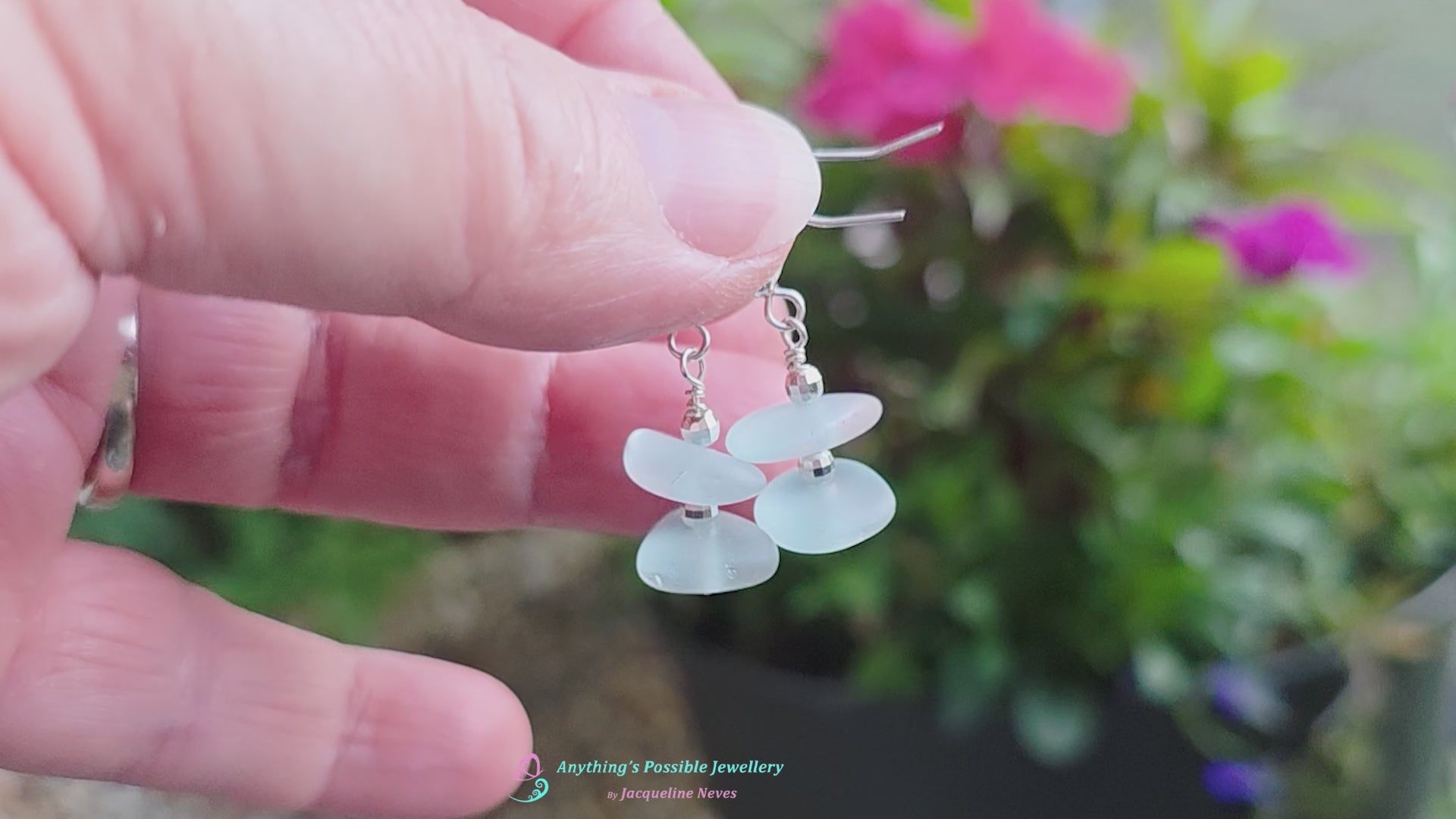 Video of Pale Aqua blue Sea glass earrings with sparkly sterling silver beads on french style earring hooks with flowers in the background and wood