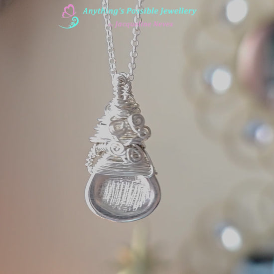 Sterling Silver Sculptural and Wire Wrapped Pendant with coils and texture on a rolo style chain with beige blurred background 