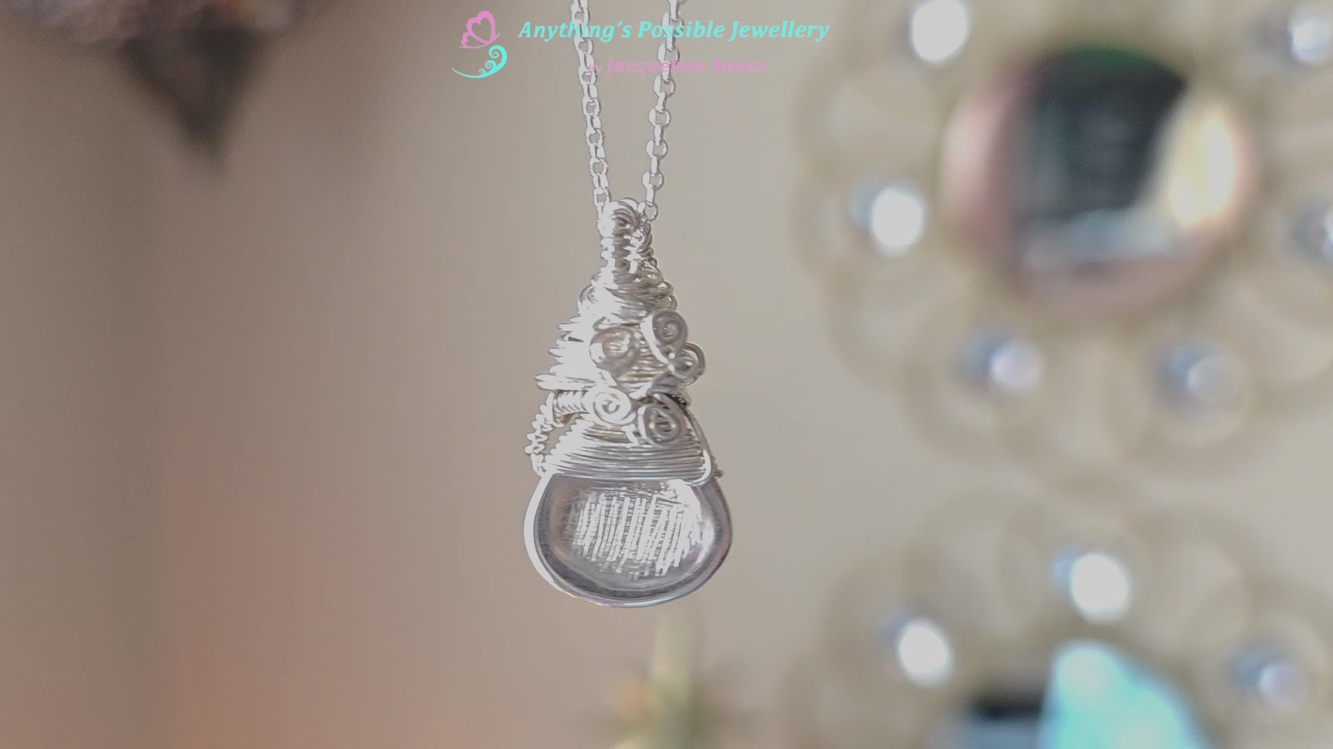 Sterling Silver Sculptural and Wire Wrapped Pendant with coils and texture on a rolo style chain with beige blurred background 