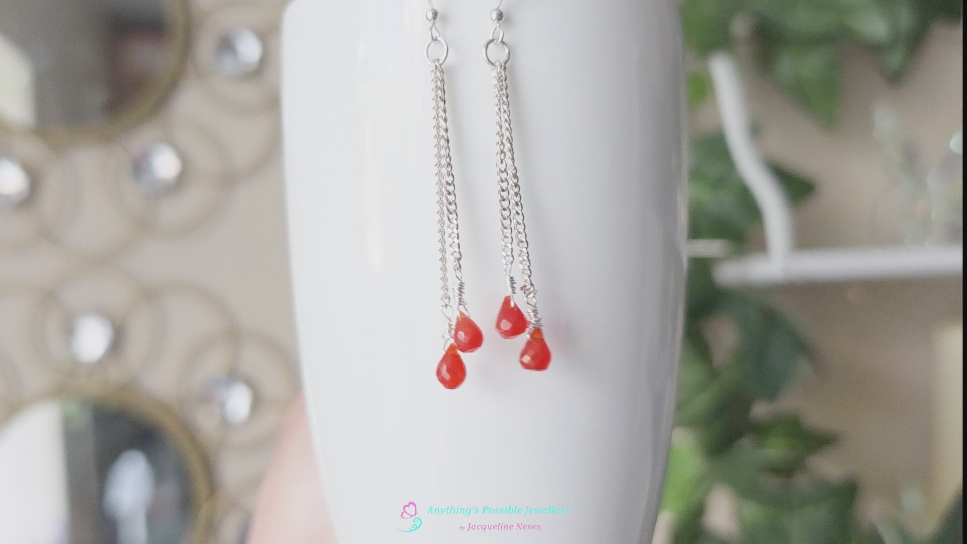Video of a pair of handmade long dangle earrings with orange faceted Carnelian drop shaped stones dangling from Sterling Silver chain 