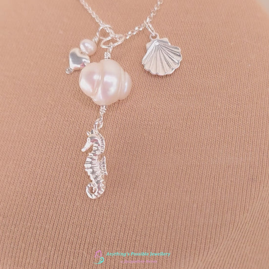 Video of Silver Necklace with white Pearls, Silver Seahorse, Shell and Heart Pendants on chain with beige background 