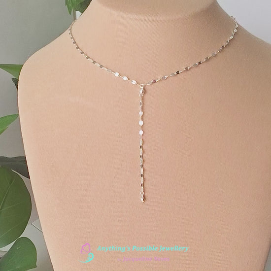 Video of a handmade Sparkly Sterling Silver Decorative Chain Lariat necklace with brilliant flat decorative chain, sparkly faceted beads on beige background