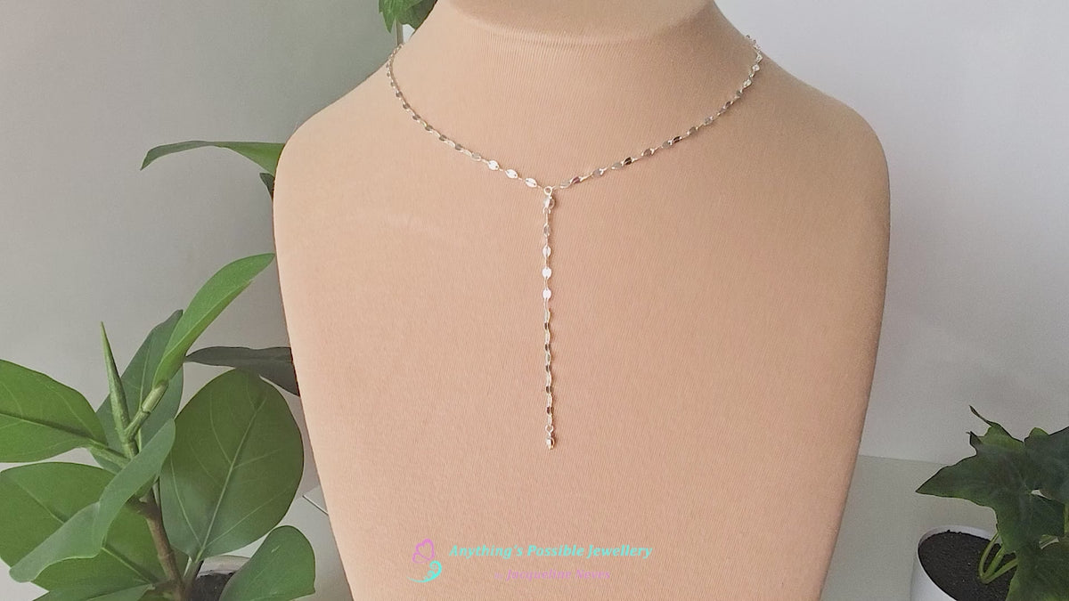 Video of a handmade Sparkly Sterling Silver Decorative Chain Lariat necklace with brilliant flat decorative chain, sparkly faceted beads on beige background