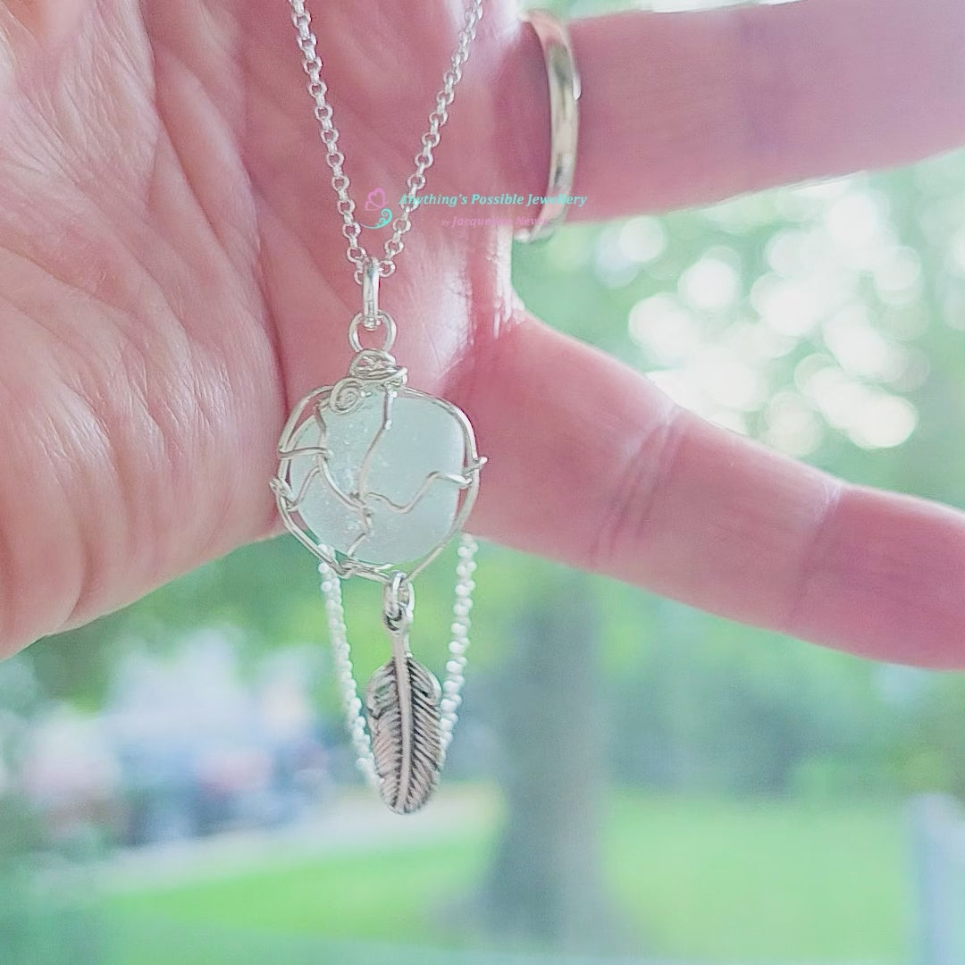Video of Silver Pendant with Aqua Blue Sea Glass and dangling Silver Feather on Silver Rolo chain displayed in hand
