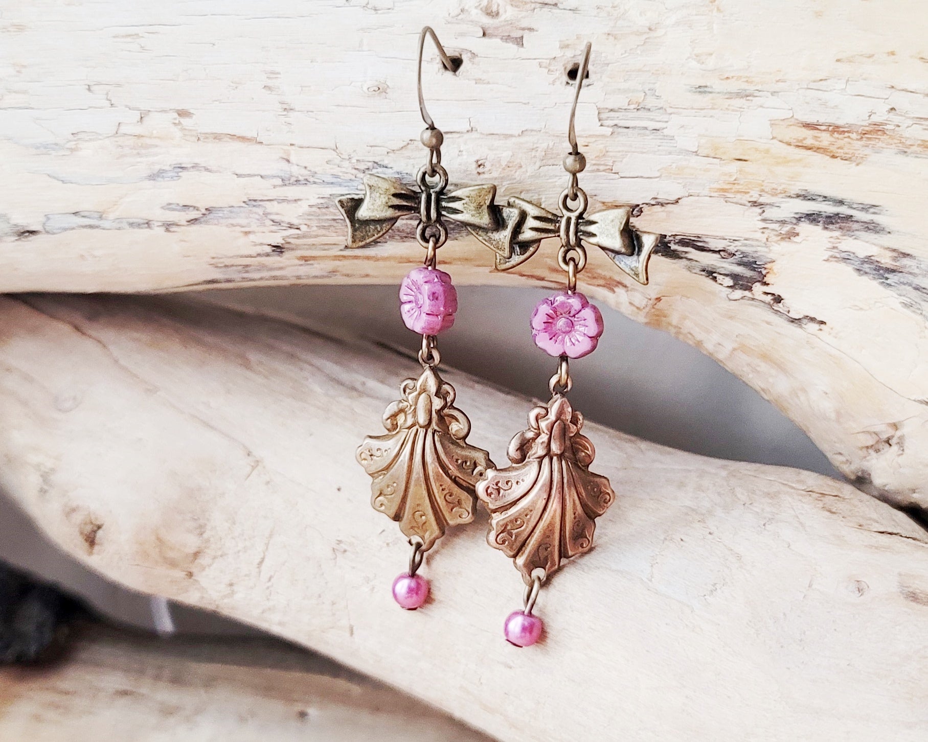 Vintage Romance Flower Shell Bow Earrings made with Upcycled Vintage Shells, Pink Flowers and Bows. Displayed on beach wood