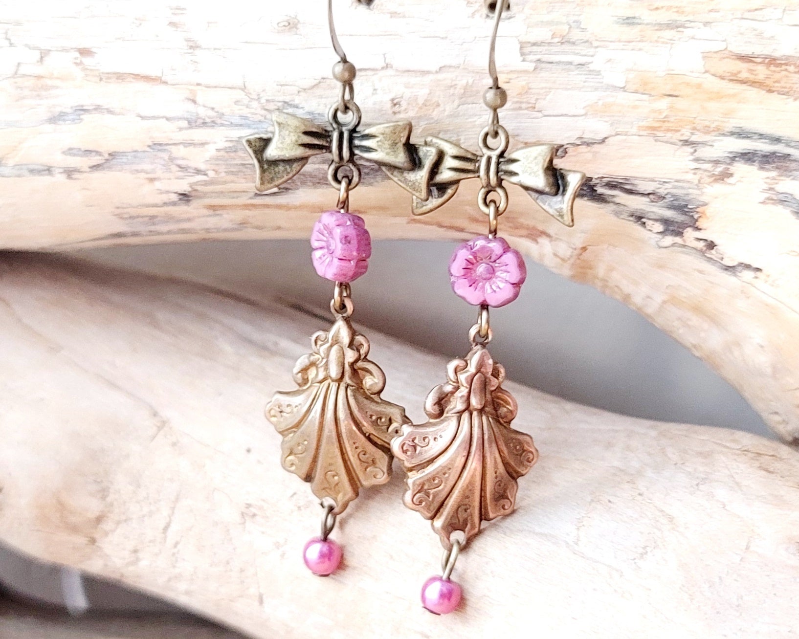 Vintage Romance Flower Shell Bow Earrings made with Upcycled Vintage Shells, Pink Flowers and Bows. Displayed on beach wood