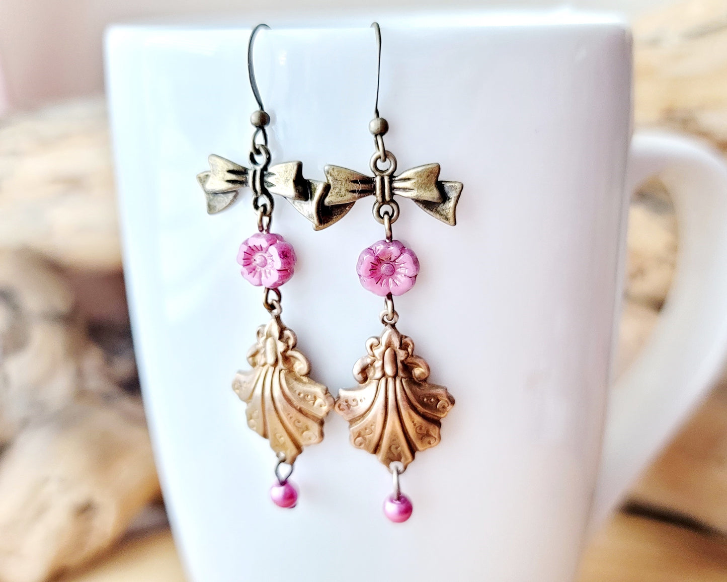 Vintage Romance Flower Shell Bow Earrings made with Upcycled Vintage Shells, Pink Flowers and Bows. Displayed on white mug