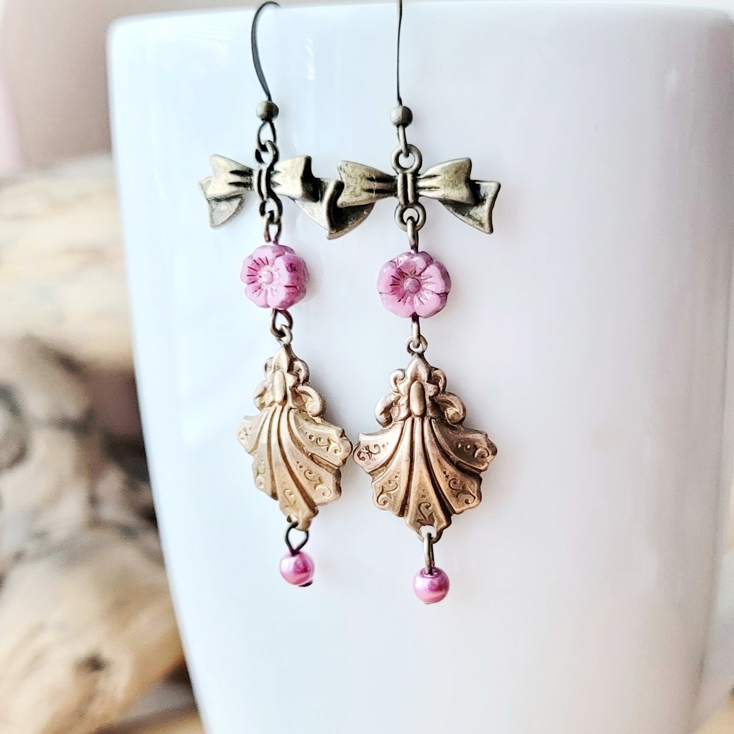 Vintage Romance Flower Shell Bow Earrings made with Upcycled Vintage Shells, Pink Flowers and Bows. Displayed on white mug