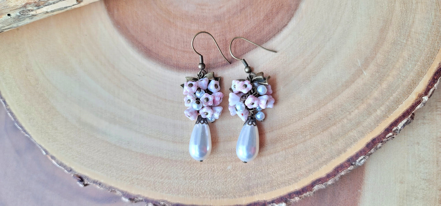 Vintage Romance White Pearl Pale Pink Flower Bow Earrings, Long Cluster earrings made with white Faux pearls and pale pink Czech flowers and Antiqued Brass finished metal.  Photo on wood background