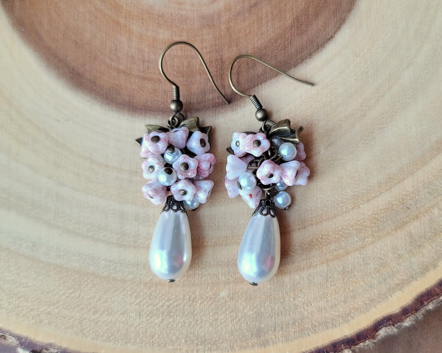 Vintage Romance White Pearl Pale Pink Flower Bow Earrings, Long Cluster earrings made with white Faux pearls and pale pink Czech flowers and Antiqued Brass finished metal.  Photo on wood background