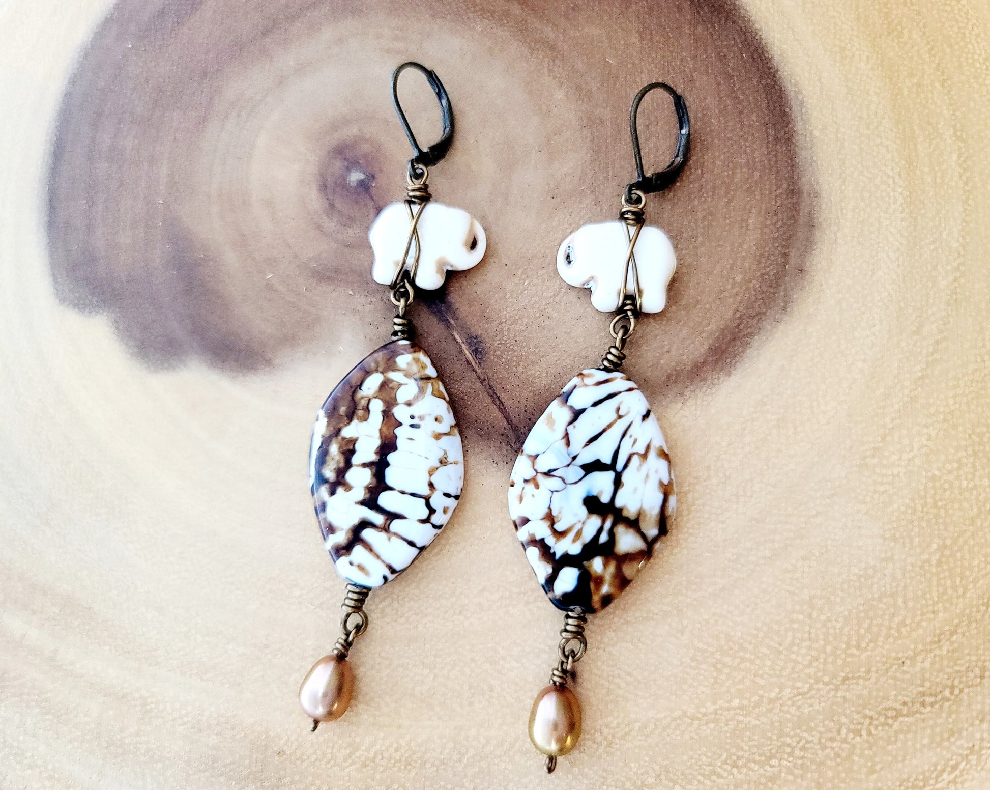 Wild Earth Elephant Earrings, Long Elephant Earrings made with Glazed Agate, Howlite, Gold Freshwater Cultured Pearl, displayed on wood