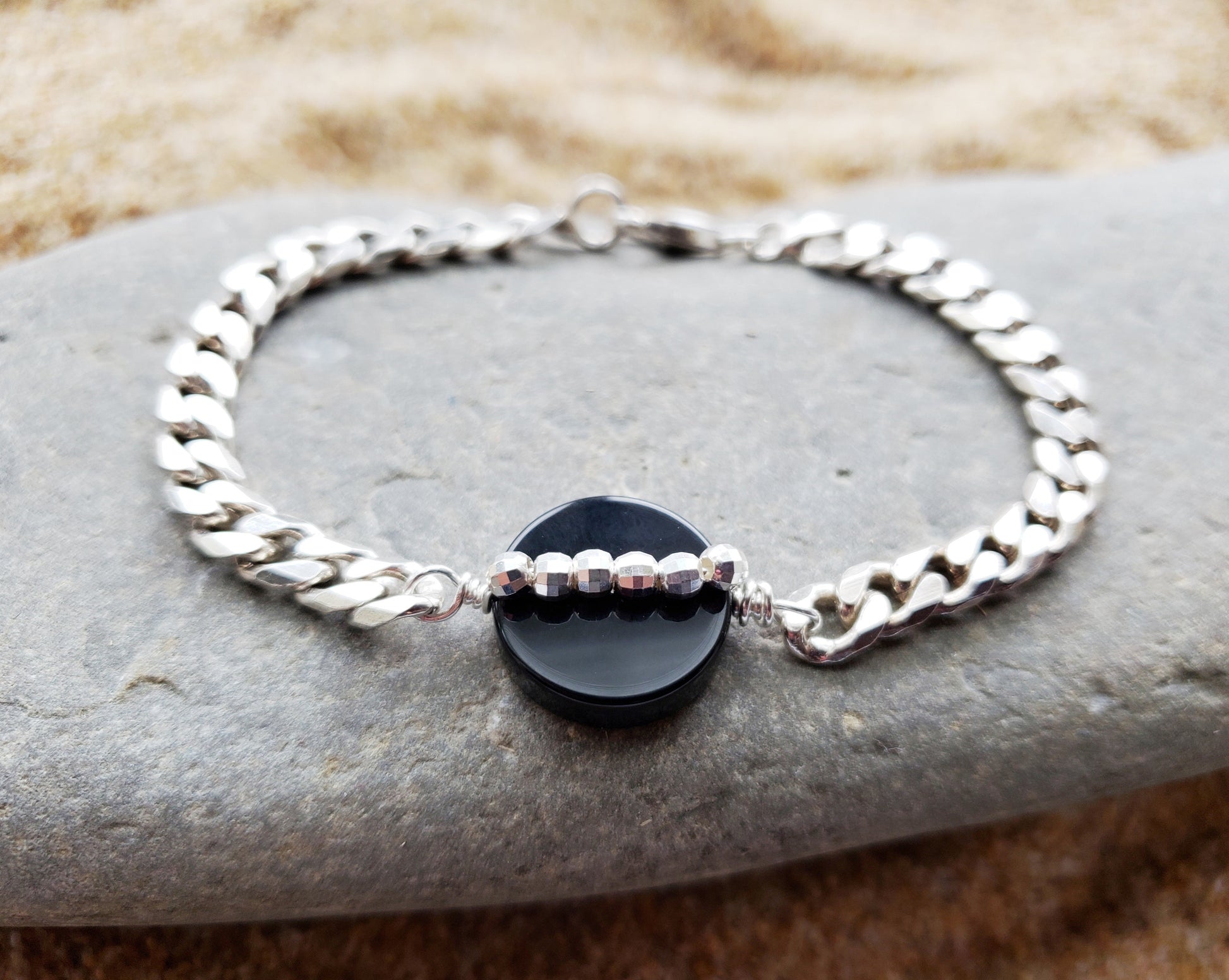 Path of Light Black Onyx Bracelet, Upcycled, Repurposed Sterling Silver Chain, round Disk shaped Onyx stone in centre with a line of sparkly Sterling Silver beads. Displayed on Stone