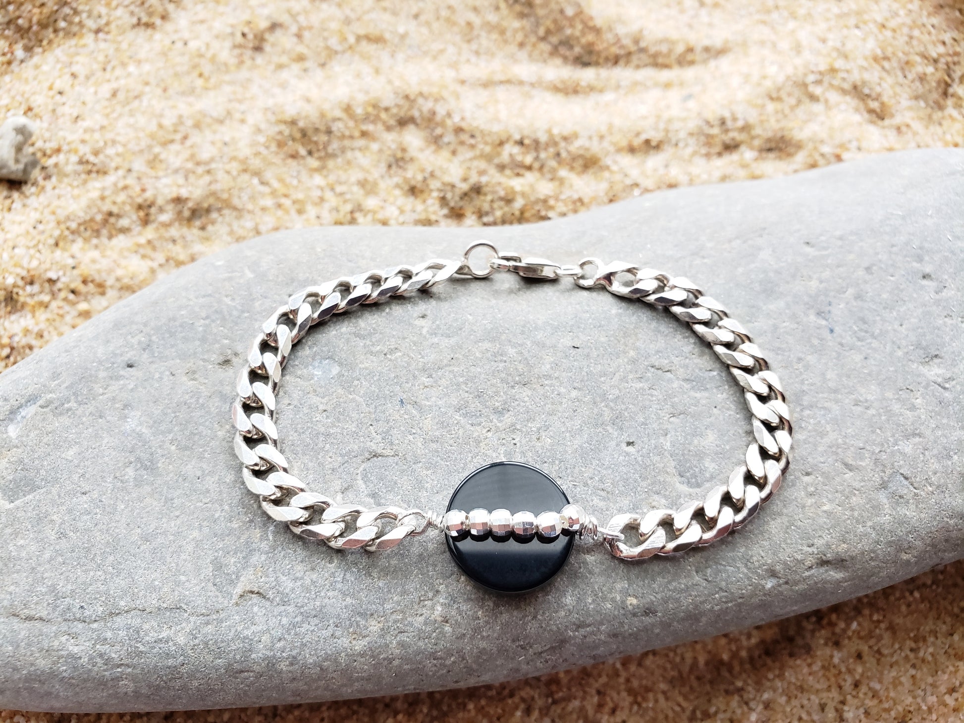 Path of Light Black Onyx Bracelet, Upcycled, Repurposed Sterling Silver Chain, round Disk shaped Onyx stone in centre with a line of sparkly Sterling Silver beads. Displayed on Stone