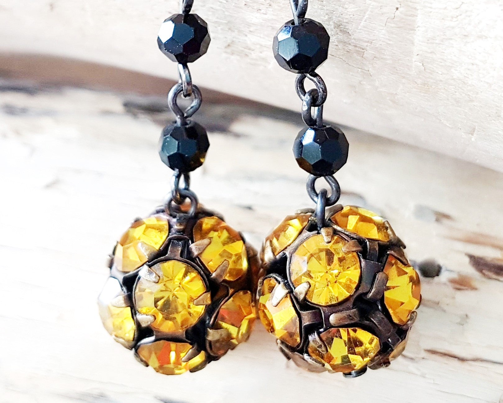 Long Art Deco Black Amber Crystal Earrings dangling on beach wood