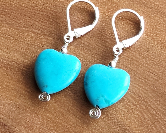 Sterling Silver Turquoise Blue Heart Dangle Earrings with small silver Celtic Eternity Coils on the base of the hearts on wood background 